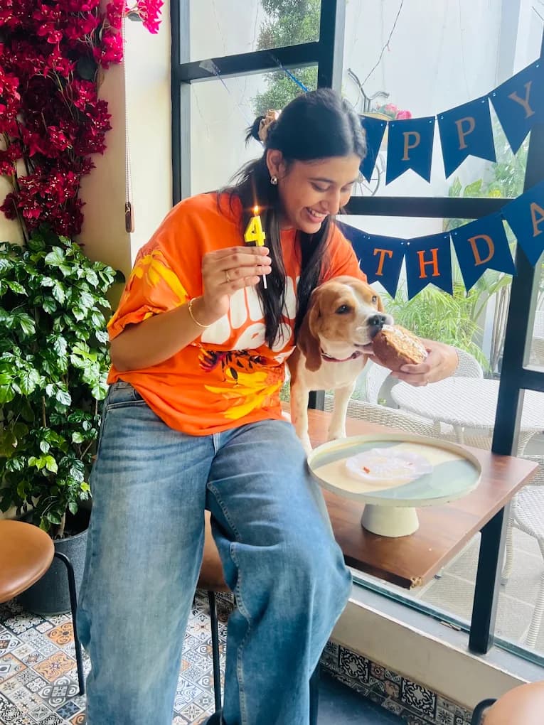 A pet parent celebrating her beagle's 4th birthday with a candle and cake at a dog birthday party in Lucknow